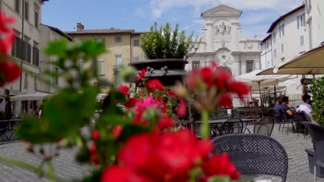 Vista-De-La-Pintoresca-Plaza-&quot;piazza-Del-Mercato&quot;-En-Spoleto,-Una-Ciudad-De-Umbría-Con-Terrazas,-Flores-Y-Un-Edificio-Antiguo-Con-Un-Reloj-Y-Una-Fuente-En-Su-Fachada