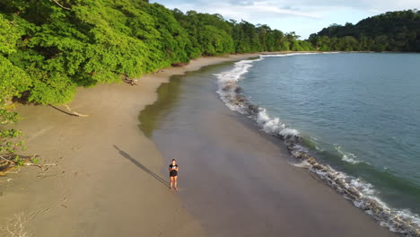 Woman-walking-over-tropical-beach-and-panning-the-drone-around-the-landscape-in-Costa-Rica