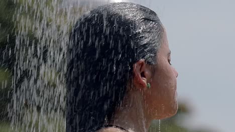 Mujer-Duchándose-En-La-Playa,-Primer-Plano-De-La-Cabeza,-Cabello-Oscuro-Latino,-Arete,-Manos-A-Través-Del-Cabello,-Lavado-De-Cabello,-Tiro-Inclinado-Hacia-Abajo