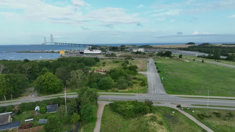 The-Great-Belt-bridge-in-Denmark-seen-from-Korsor---Aerial-showing-old-belt-strait-ferry-and-toll-checkpoint-with-bridge-in-background-horizon