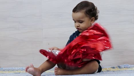 Niedlicher-Kleinkind-Junge,-Der-Drinnen-Mit-Rotem-Warping-Papier-Spielt