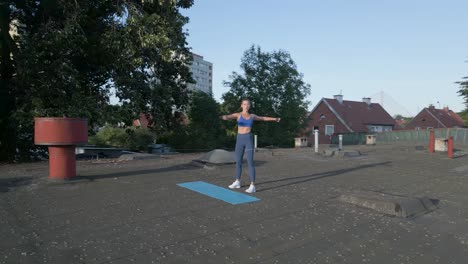 Wide-tracking-shot-around-a-woman-as-she-does-stretches-on-a-rooftop