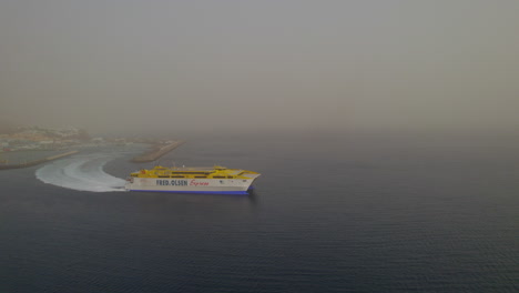 aerial-view-with-lateral-tracking-of-the-ferry-leaving-the-port-of-Morro-Jable-and-on-a-day-with-a-lot-of-haze-in-the-atmosphere