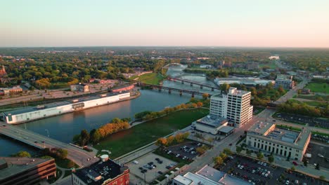 orbiting-aerial-at-sunet-towards-Rock-River-and-bridges-then-revealing-beautiful-downtown-Rockford-Illinois-from-America