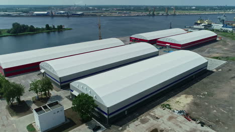 Massive-grain-warehouse-buildings-near-river,-aerial-drone-view