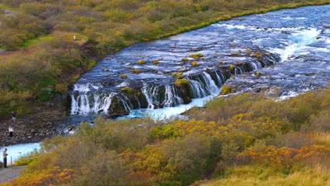 Aerial-revealing-shot-of-tourists-watching-Bruararfoss-waterfall-from-a-bridge-in-Iceland