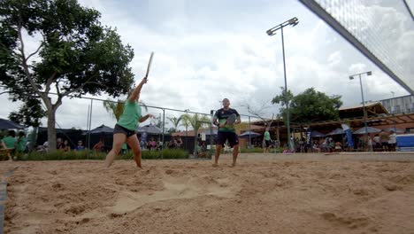 Mixed-doubles-team-playing-an-exciting-volley-in-beach-tennis-match