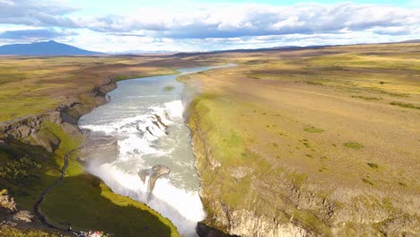 High-aerial-shot-of-tourists-overlooking-the-Gullfoss-Falls-flowing-through-the-countryside