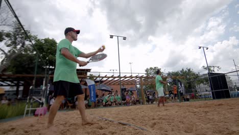 Spectators-watching-on-as-men’s-beach-tennis-double-team-battles-for-the-point