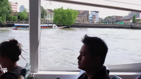 People-aboard-a-river-cruise-boat-enjoy-the-sights-along-the-Chao-Phraya-river,-a-gateway-to-major-tourist-attractions-in-Bangkok,-Thailand