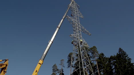 Repair-on-a-power-pole-while-electricians-secured-with-protective-equipment-repair-the-power-lines-with-a-lifting-platform-for-a-functioning-infrastructure-and-power-supply-on-a-cloudless-day