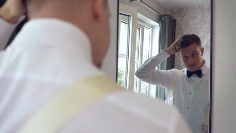 Groom-putting-his-necktie-perfectly-in-front-of-a-mirror,-preparing-for-the-wedding