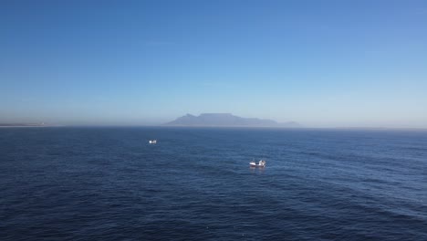 Dos-Barcos-De-Pesca-En-Los-Océanos-Con-La-Montaña-De-La-Mesa-En-El-Horizonte