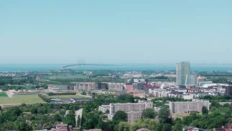 Telephoto-sideways-aerial-over-Swedish-city-Malmö-and-Oresund-bridge,-copyspace