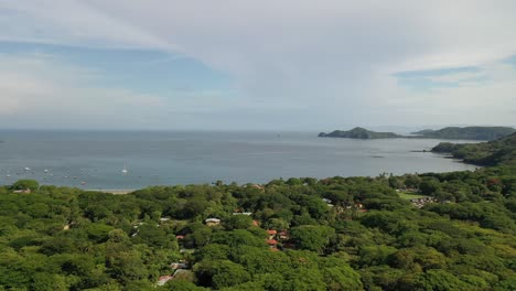 Aerial-panoramic-pan-across-Playa-Hermosa,-Guanacaste-Region,-Costa-Rica