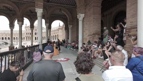 Tourists-gather-underneath-grand-arches-of-Plaza-de-Espana-watching-street-performers