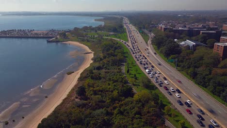 An-aerial-time-lapse-of-the-heavy-traffic-on-the-Belt-Parkway-and-the-the-shores-of-Jamaica-Bay-on-a-sunny-day-in-Brooklyn,-NY