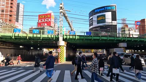Multitud-De-Personas-Cruzando-Una-Carretera-Muy-Transitada-En-Shinjuku-Toyko,-Japón