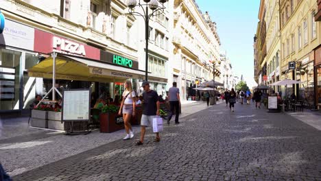 Cobblestone-and-touristy-streets-with-stores-and-restaurants-on-a-sunny-day-in-Prague,-Czech-Republic