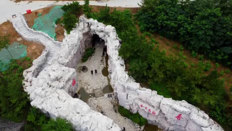 Aerial-forward-dolly-view-over-Huaxiacheng-park-above-rocky-pathway-and-tunnel-in-Weihai-city
