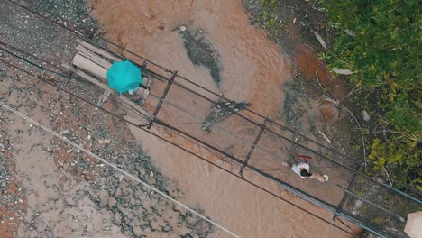 Lokaler-Wohnsitz-Von-Mabini,-Der-Den-überfluteten-Fluss-überquert,-Indem-Er-Auf-Einer-Alten-Verrosteten-Brücke-Geht