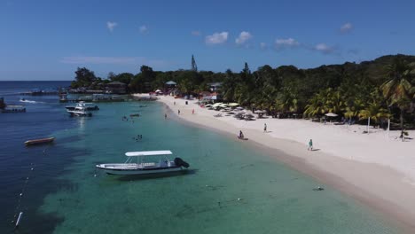 Low-aerial-view-of-tourists-on-sand-beach-on-West-Bay-Roatan,-Honduras
