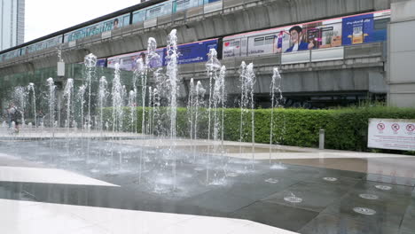 Käufer-Gehen-Und-Fotografieren-Vor-Einem-Brunnen-An-Einem-Gehweg,-Der-Die-Beiden-Einkaufszentren-Siam-Paragon,-Siam-Discovery-Und-Den-BTS-Bahnhof-In-Bangkok,-Thailand,-Verbindet