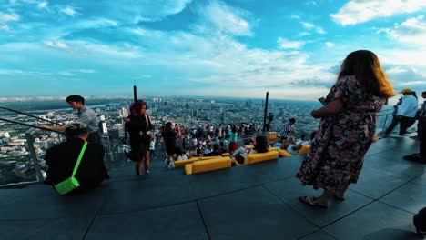 Weite-Aussicht-Auf-Menschen,-Die-Sich-Auf-Der-Dachterrasse-Entspannen-Und-Die-Stadt-Bei-Sonnenuntergang-überblicken