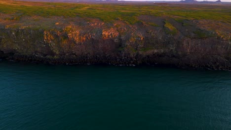 Aerial-revealing-shot-of-a-coastal-cliff-face-during-sunset-in-Iceland