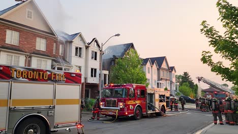 Bomberos-Y-Camiones-De-Bomberos-En-Un-Barrio-Residencial,-Extinguiendo-El-Incendio-De-La-Casa-Durante-El-Día.