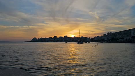 Mittelmeerküstenstadt-Saranda,-Sonnenuntergang-über-Dem-Hafen-Und-Ruhige-Meeresbucht-–-Eine-Fesselnde-Reise-Durch-Die-Abenddämmerung