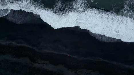 Breathtaking-aerial-view-from-Reynisfjara-Black-Sand-Beach-during-summer-in-Iceland-where-beach-waves-are-contrasting-with-the-beautiful-dark-sand