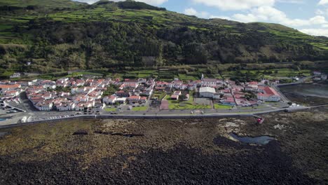 Drone-pullback-view-of-Lajes-do-Pico-coastal-village-on-rugged-shoreline,-Azores