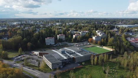Aerial-flyover-green-football-soccer-field-at-school-in-Finland-city
