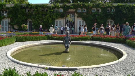 Hermosa-Fuente-De-Una-Joven-En-Los-Jardines-Del-Palacio-Mirabell-Con-Un-Gran-Grupo-De-Turistas