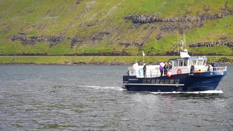 Blue-and-white-boat-with-a-Faroese-flag-drives-in-waters-of-Mykines-to-Sorvagur-in-Vagar-Island