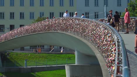 Fußgänger-Gehen-Auf-Der-Marko-Feingold-Brücke,-Die-Voller-Herzförmiger-Schlösser-Ist