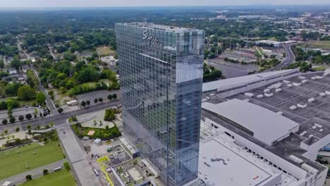 Aerial-tilt-down-shot-of-modern-Signia-Hilton-hotel-in-Atlanta-City-during-sunny-day,-USA