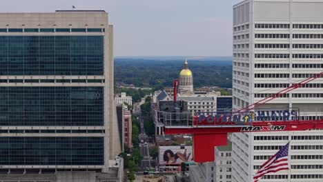 Aerial-trucking-shot-of-Centennial-Yards-Crane-and-waving-american-flag-with-George-Capitol-Museum