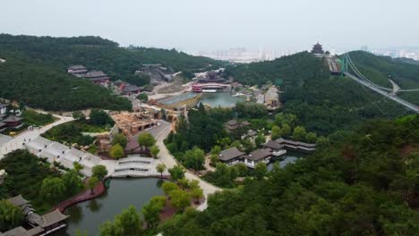 Dynamic-aerial-left-pan-view-of-Huaxiacheng-glass-bridge-and-water-park-in-Weihai,-China