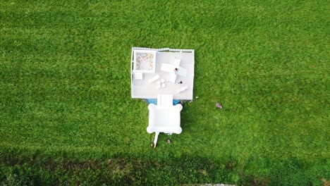 Top-down-aerial-view-of-a-big-white-bouncy-castle-in-a-field-of-grass