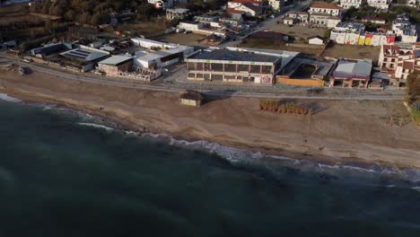 Kinoaufnahmen-Aus-Der-Umlaufbahn-Von-Vama-Veche,-Rumäniens-Küstenjuwel,-In-Einer-Atemberaubenden-Luftaufnahme-über-Das-Schwarze-Meer-Und-Die-Unberührte-Küste,-Die-Bei-Sonnenaufgang-Von-Schäumenden-Wellen-Getroffen-Wird