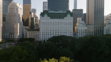 Drone-shot-low-over-the-Central-park,-toward-the-Plaza-hotel,-in-sunny-New-York,-USA