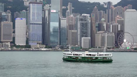Star-Ferry-Fährt-Durch-Den-Hafen-Mit-Blick-Auf-Skyline-Gebäude-Unter-Grauem,-Dunstigem-Himmel-Aufgrund-Von-Luftverschmutzung,-Hongkong,-China