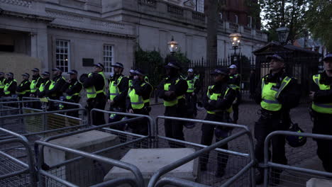 Eine-Einheit-Großstädtischer-Bereitschaftspolizei-In-Schützenden-Schwarzen-Overalls-Und-Nato-Helmen-Am-Gürtel-Bildet-Während-Eines-Protestes-Eine-Absperrung-Hinter-Metallenen-Absperrgittern-Vor-Der-Israelischen-Botschaft-In-London