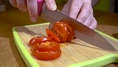Knife-cuts-tomato-on-wooden-board-Slow-motion-with-rotation-tracking-shot.