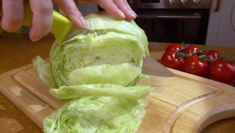 Knife-cuts-salad,-lettuce-on-wooden-board-Slow-motion-with-rotation-tracking-shot.
