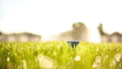 Golf-club-hits-a-golf-ball-in-a-super-slow-motion.-Drops-of-morning-dew-and-grass-particles-rise-into-the-air-after-the-impact.