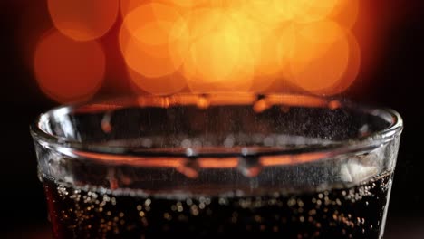 Cola-with-splashing-bubbles-slow-motion-on-a-blurry-light-,blurry-background.