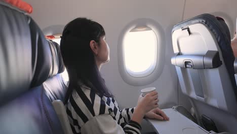 Frau-Sitzt-Im-Flugzeug,-Schaut-Aus-Dem-Fenster-Und-Trinkt-Kaffee.